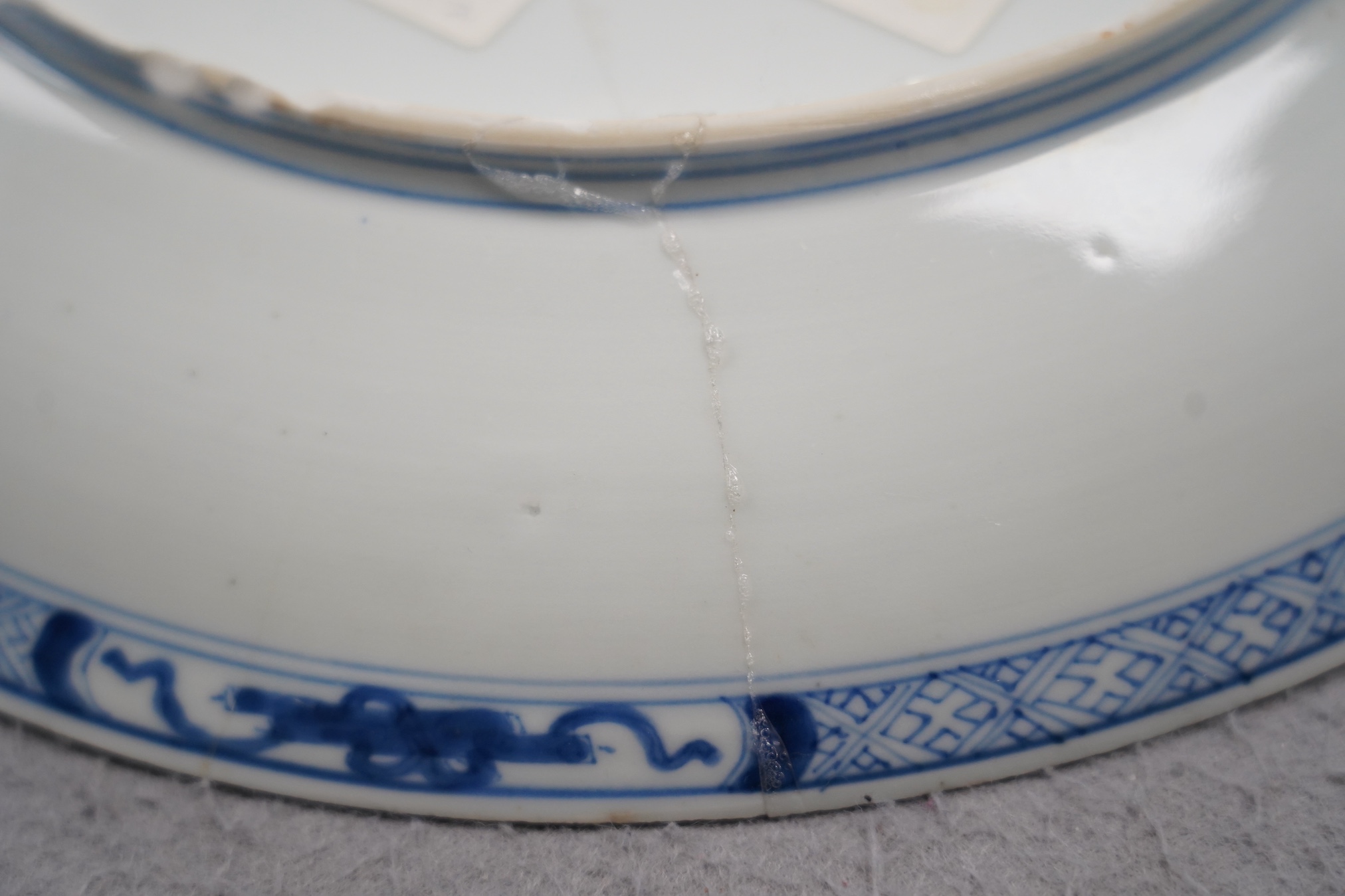A Chinese blue and white dish, Kangxi period, broken and messily reglued